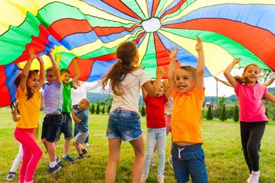 Boston Summer Camps | Kids under a colorful Parachute playing a game